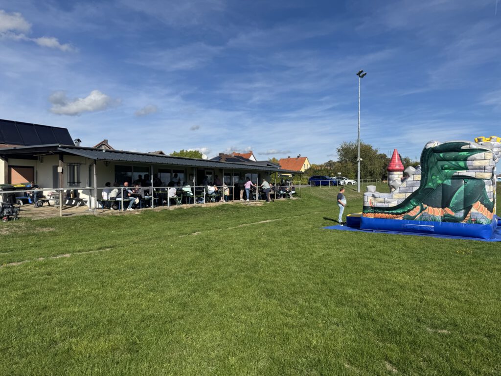 Vereinsheim und Hüpfburg auf dem Vereinsgelände bei sonnigem Wetter.